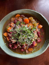 Bowl of vegetable stew with beans and carrots on a wooden table